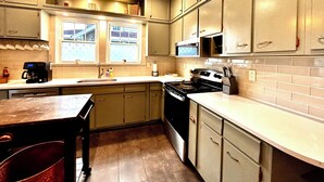 A kitchen with a stove, microwave, and a hanging light fixture.