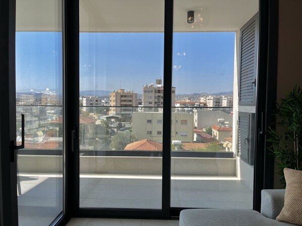 A balcony with a view of a cityscape, including buildings and a distant mountain range. - 107 LIM - Stay Mouson View Apartment (Limassol)