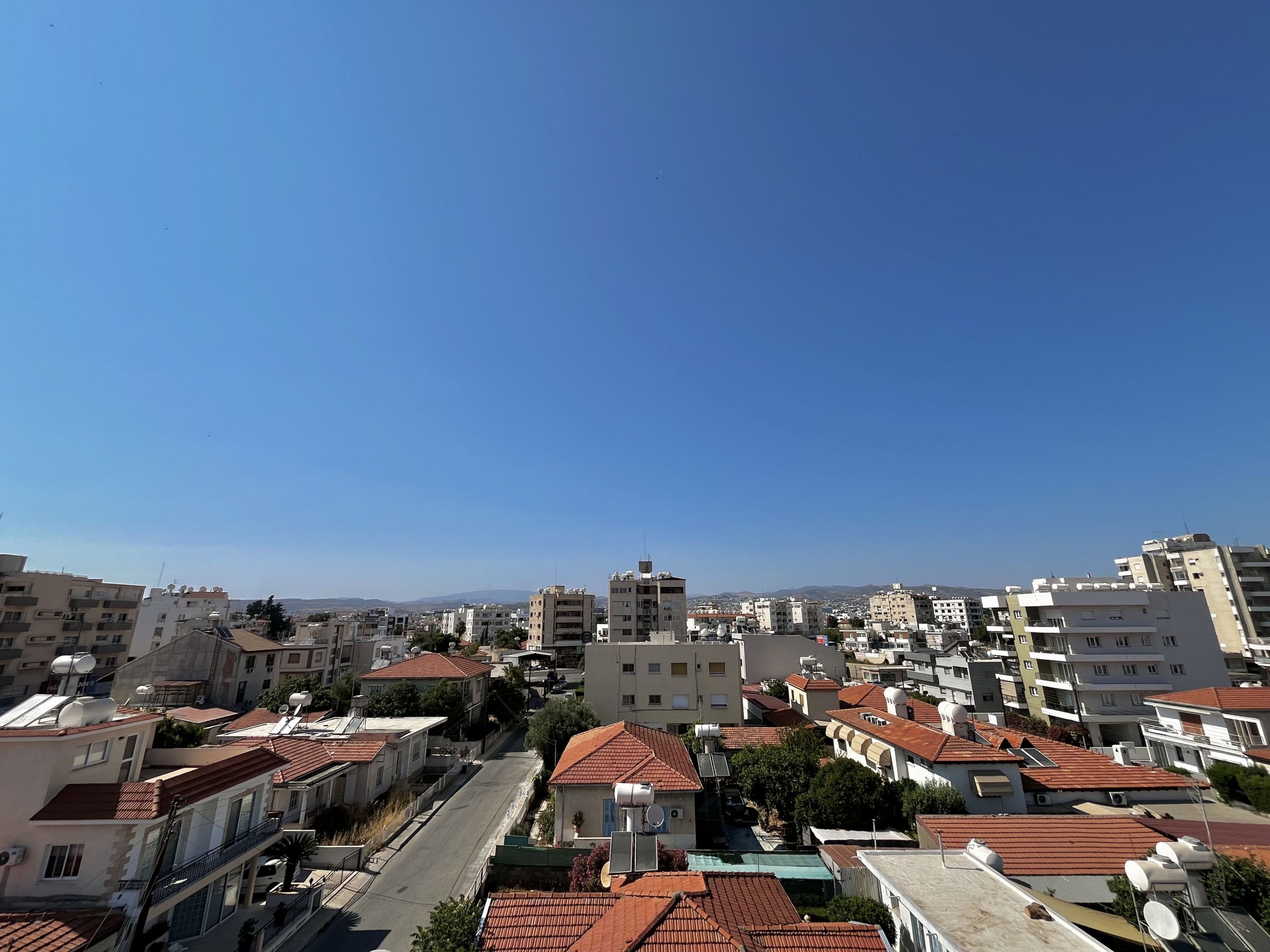 A residential area with multiple buildings, some with red-tiled roofs and others with flat roofs.