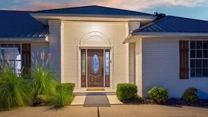 A single-story house with a symmetrical facade, a central entrance with a decorative door, and a small front yard with landscaping.