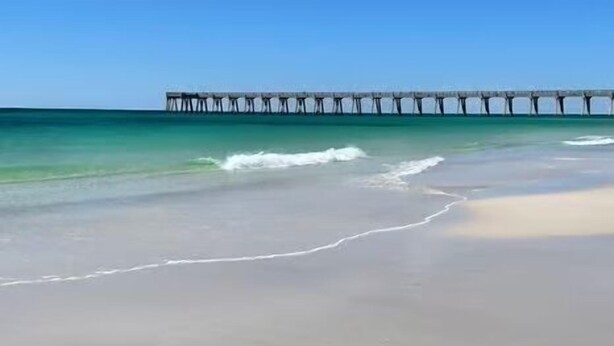 A beach with a pier extending into the ocean.