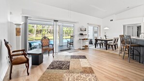 A spacious living area with a large wooden dining table, a sofa, and a ceiling fan. - Charming Retreat in Palm Bay, FL (Palm Bay)