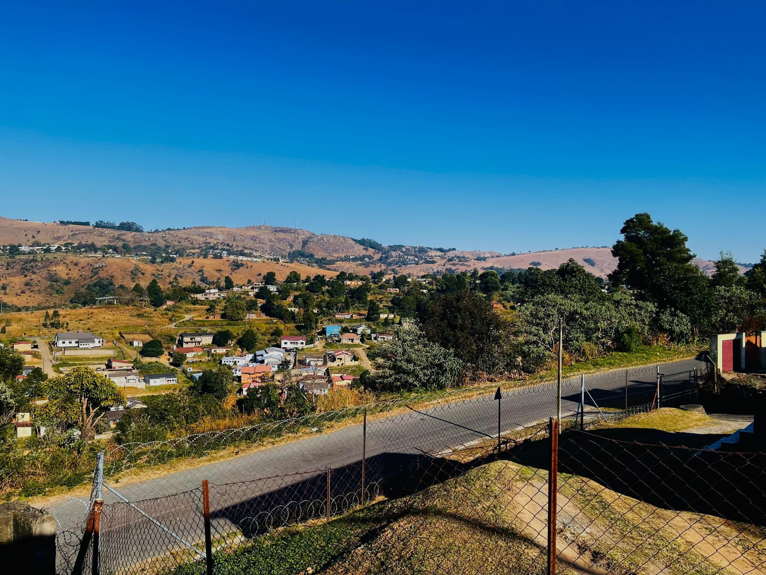 Een woonwijk met huizen, een weg en heuvels op de achtergrond.
