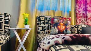 A bedroom with a patterned bedspread, a small table with a vase of flowers, and a decorative pillow.