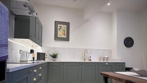 A modern kitchen with grey cabinets, a marble backsplash, a sink, and a clock on the wall.