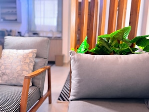 A modern living room with a grey sofa, patterned cushions, and a wooden chair.
