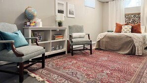 Une chambre confortable avec un grand lit, deux fauteuils, une bibliothèque et un globe terrestre posé sur une table d’appoint.
