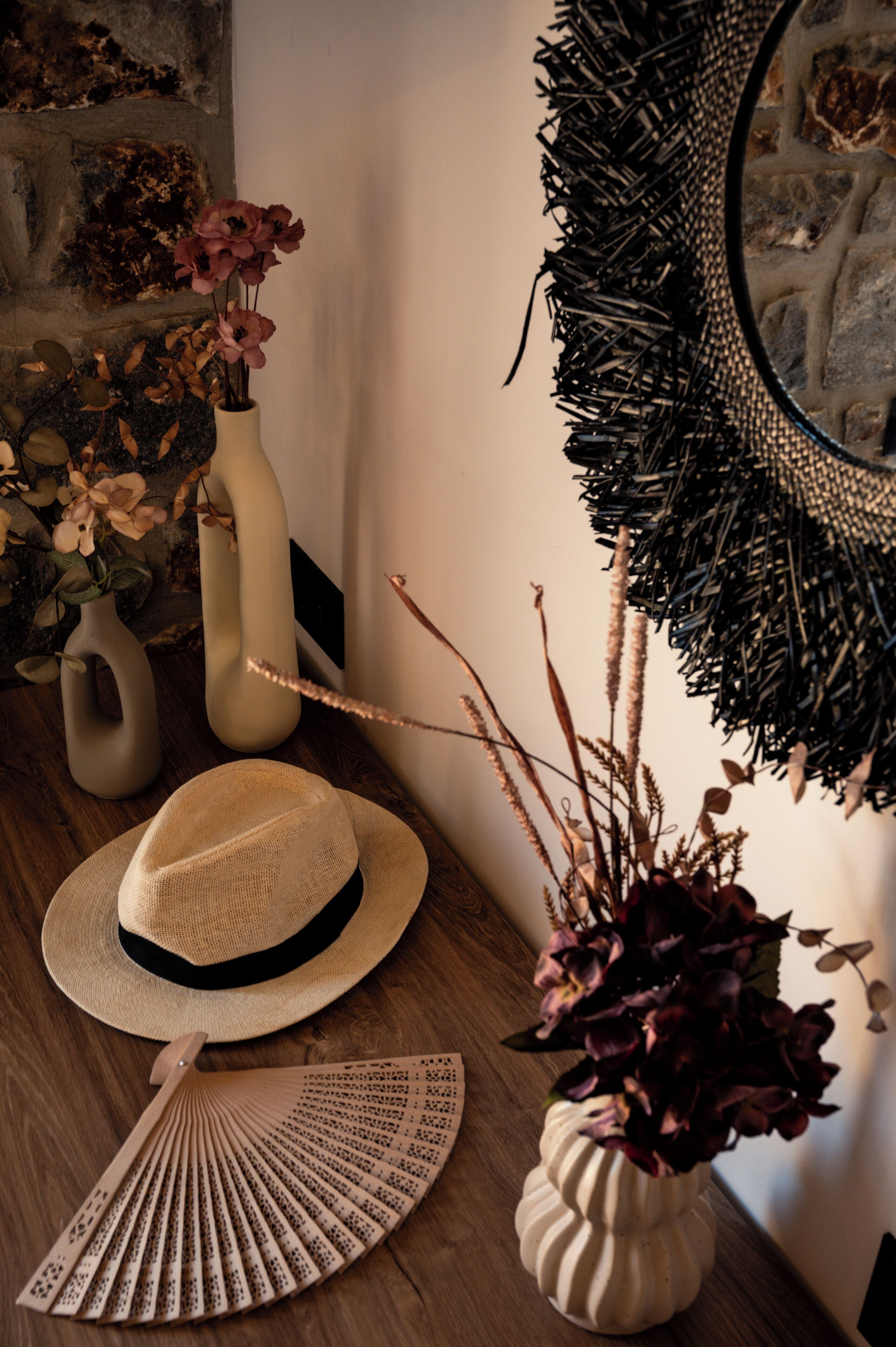 Un tavolo di legno con una ventola, un cappello e due vasi con fiori.