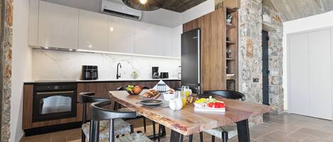 A modern kitchen with a wooden dining table, built-in appliances, and a stone accent wall.