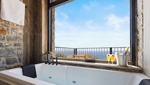 Une baignoire donnant sur la mer, avec une fenêtre.