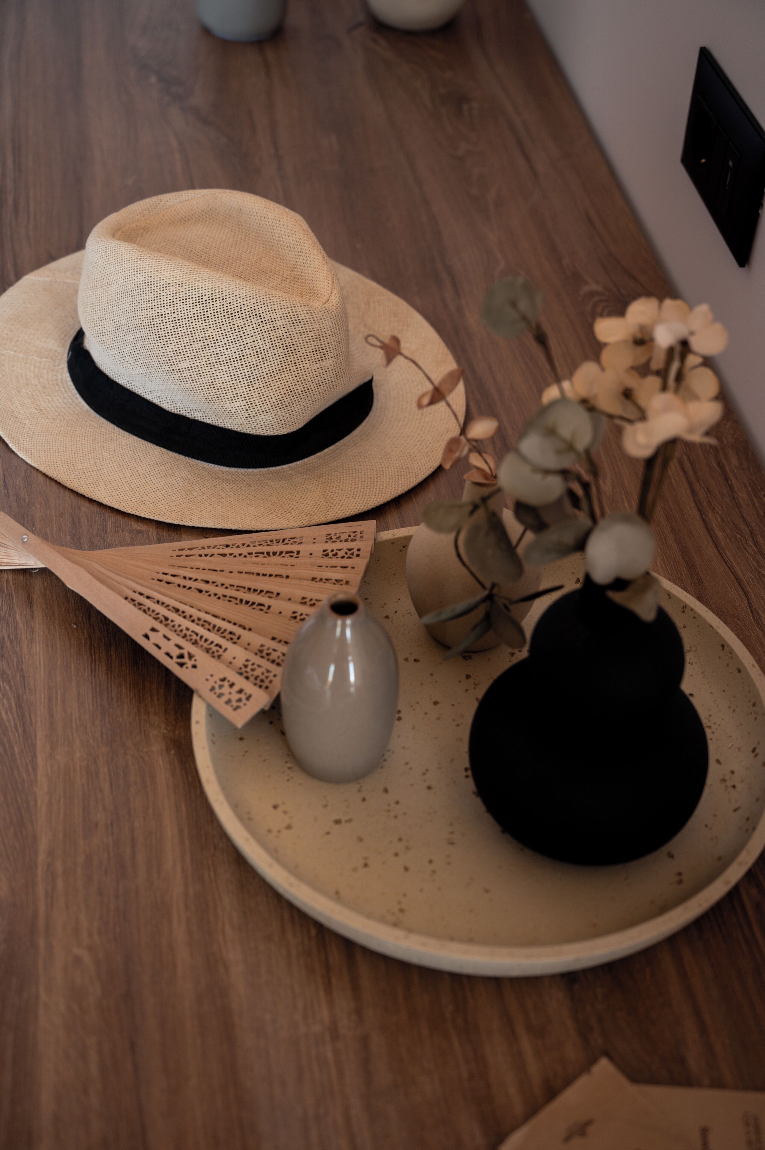 Un chapeau, un éventail, un vase et une assiette sur une table en bois.