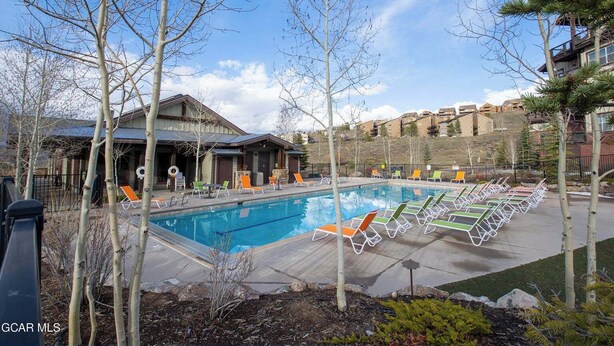 Une piscine avec des chaises longues et un bâtiment doté d’un patio couvert.