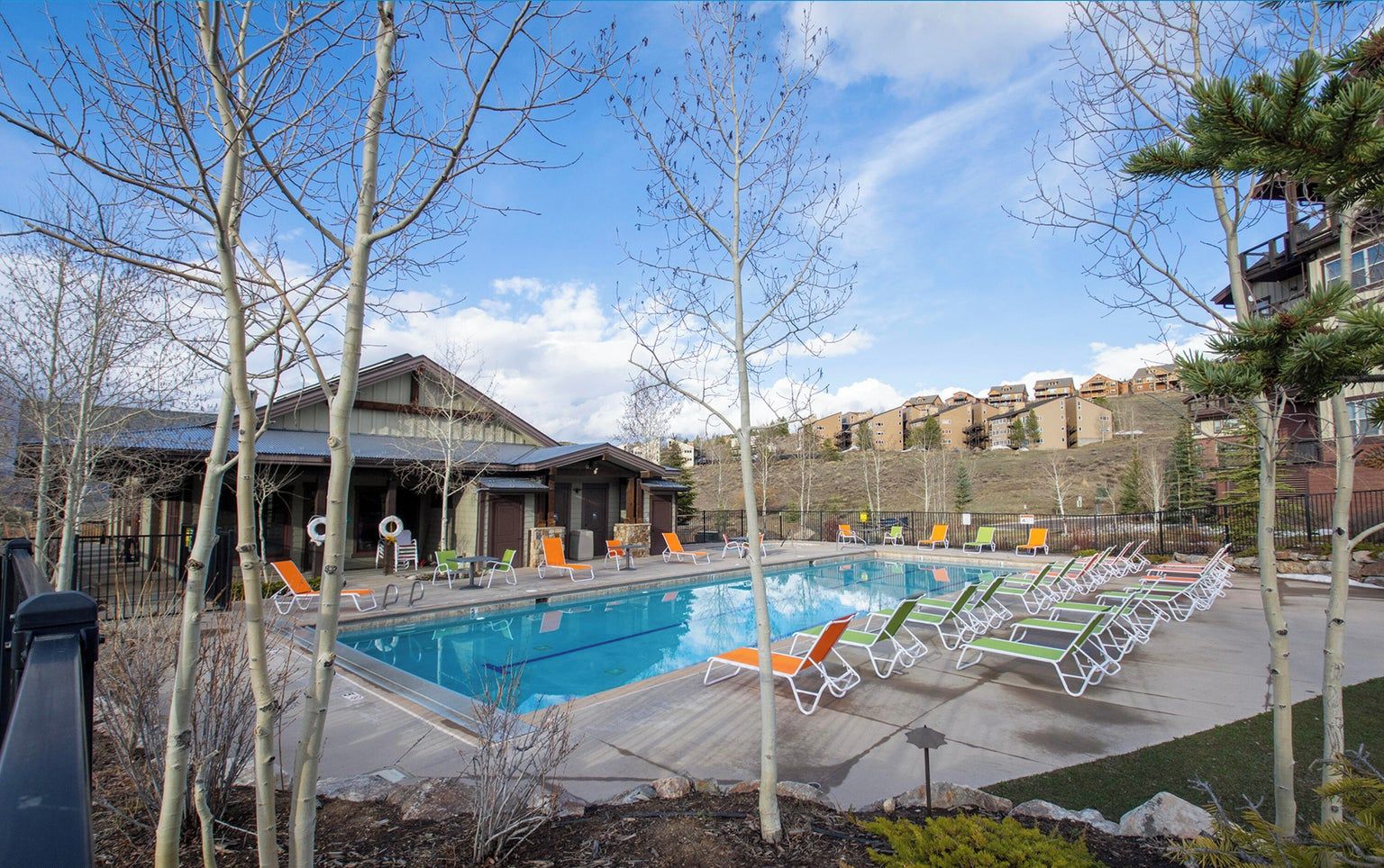 Une piscine avec des chaises longues et un bâtiment doté d’un patio couvert.