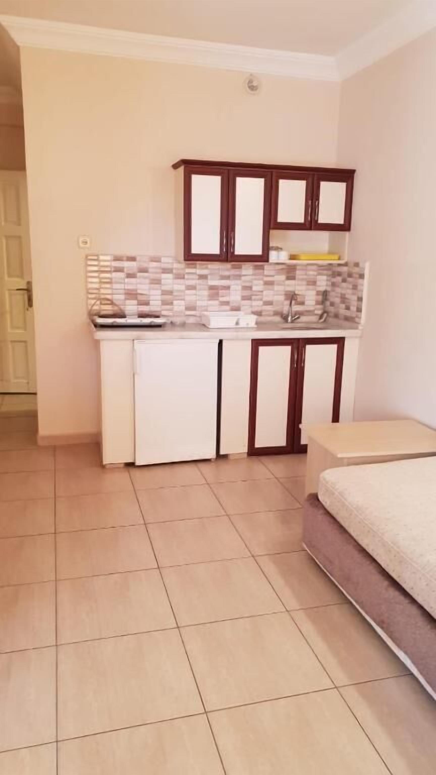 A compact kitchen with white cabinets, a tiled backsplash, and a small countertop.