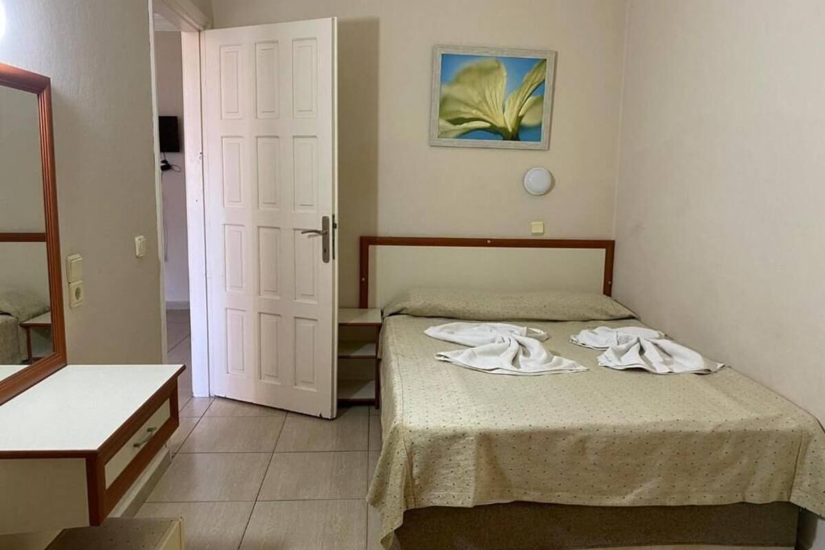 Un dormitorio con cama, mesita de noche, espejo y puerta.
