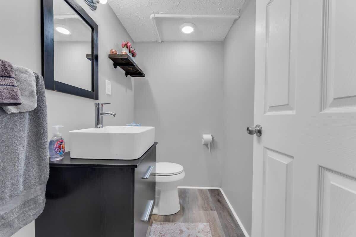 A bathroom with a white sink, a toilet, a mirror, and a towel hanging on the wall.