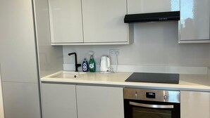 Una cocina moderna con armarios blancos, una campana extractora negra y un horno de acero inoxidable.