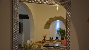 A mirror with a textured frame reflecting a dining area with a table, chairs, a vase with flowers, and a potted plant. - Cabarete Center, 1BR Apartment with Sea View (Cabarete)