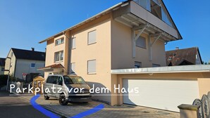 Ein zweigeschossiges Haus mit Garage, einem abgestellten Volkswagen-Transporter und einer sichtbaren Auffahrt.