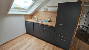 Eine kleine Küche mit Oberlicht, dunklen Schränken und einer Holz Arbeitsplatte.