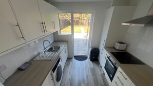 A compact kitchen with a built-in washing machine, a sink, and a toaster.