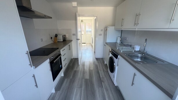 A modern kitchen with a built-in oven, microwave, and washing machine.