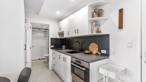 A modern kitchen with white cabinets, a black backsplash, and a built-in oven.