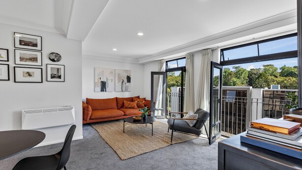A modern living room with a sofa, coffee table, and a view of the outdoors.
