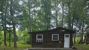 Une petite cabane en bois avec une véranda, deux fenêtres et une porte.