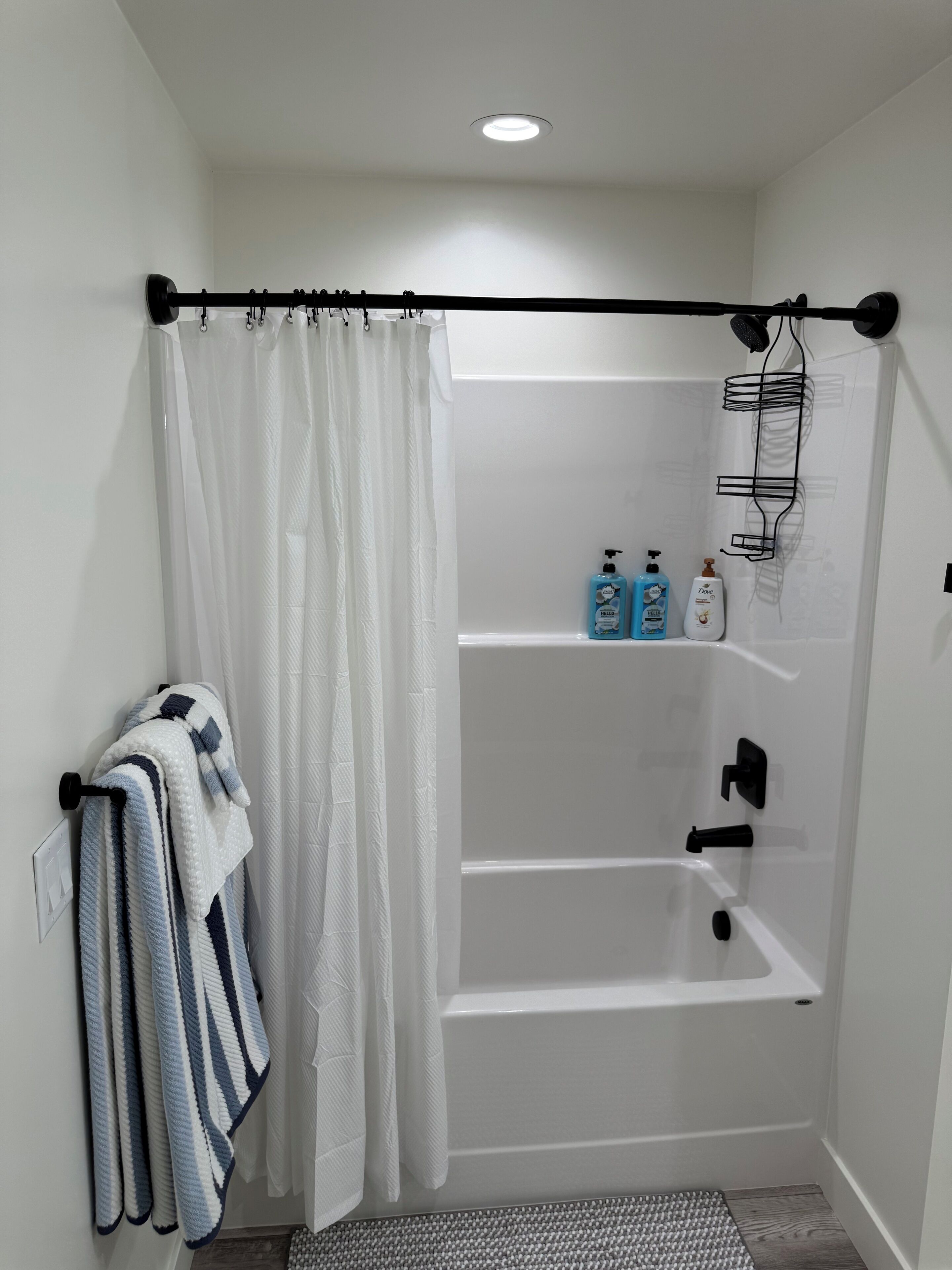 Un baño moderno con una bañera blanca, una cortina de ducha y un toallero con toallas a rayas.