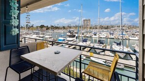 A balcony with a table and chairs overlooking a marina with numerous boats. - Gorgeous Condo | Marina Views | Steps from Harbor Beach 208B (Oceanside)