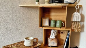 Une étagère en bois avec une machine à café, des tasses et un petit cactus.