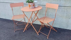 Une petite table d’extérieur accompagnée de deux chaises assorties, d’une plante en pot et d’un objet décoratif.