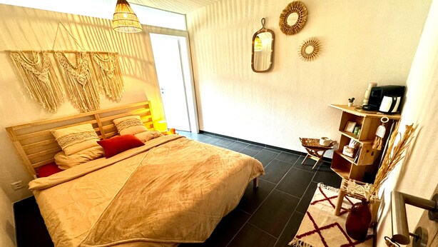 Une chambre à coucher comprenant un lit, une table de chevet, une lampe, un miroir et une étagère avec des objets décoratifs.