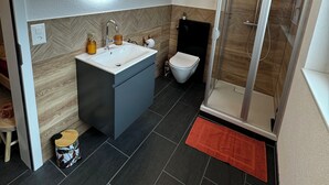 Une salle de bain moderne avec un grand miroir rond, un lavabo, des toilettes et une douche.