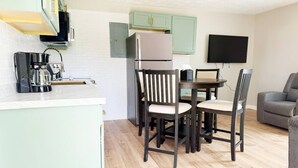 Ett kompakt bostadsutrymme med ett litet kök, en matplats och en sittgrupp.