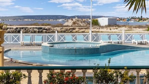 Ein Pool mit Blick auf das Meer und entfernte Gebäude.