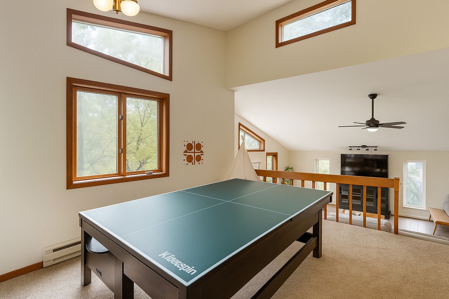 Una habitación amplia con mesa de ping pong, televisor y ventilador de techo.