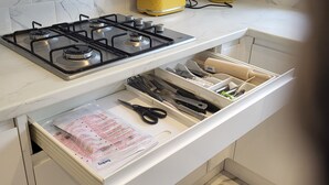 Une cuisine moderne équipée d’une cuisinière à gaz, d’une bouilloire jaune et d’un organiseur de tiroir.