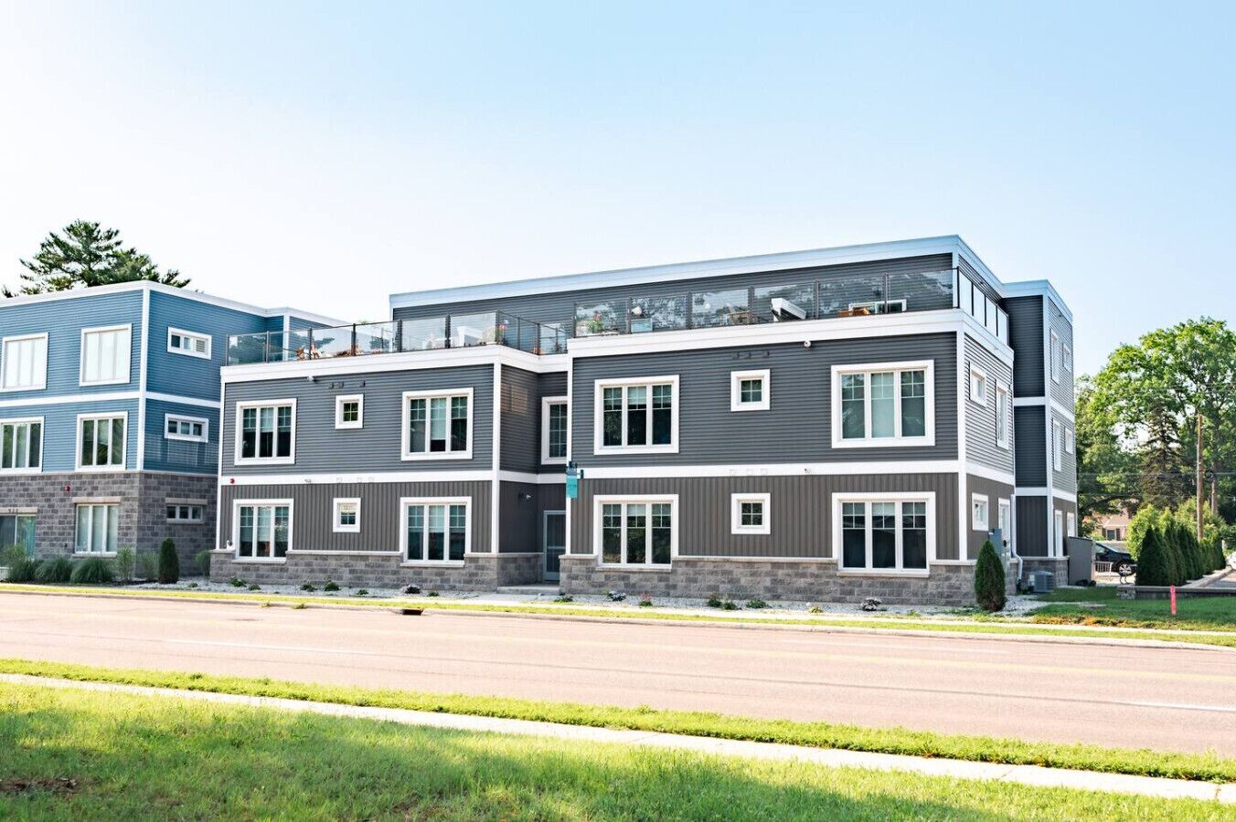 A multi-story residential building with a modern design, featuring a mix of window styles and a prominent balcony on the upper floor.