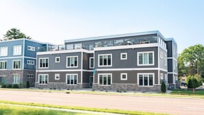 Un edificio residencial de varios pisos con un diseño moderno, que presenta una variedad de estilos de ventanas y un balcón prominente en el piso superior.
