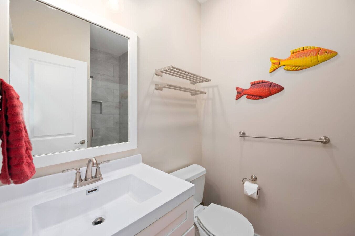 A bathroom with a white sink, a toilet, a towel rack, and two fish wall decals.