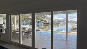 Una habitación con puerta corrediza de vidrio que da a una zona de piscina con vistas a un puerto deportivo.