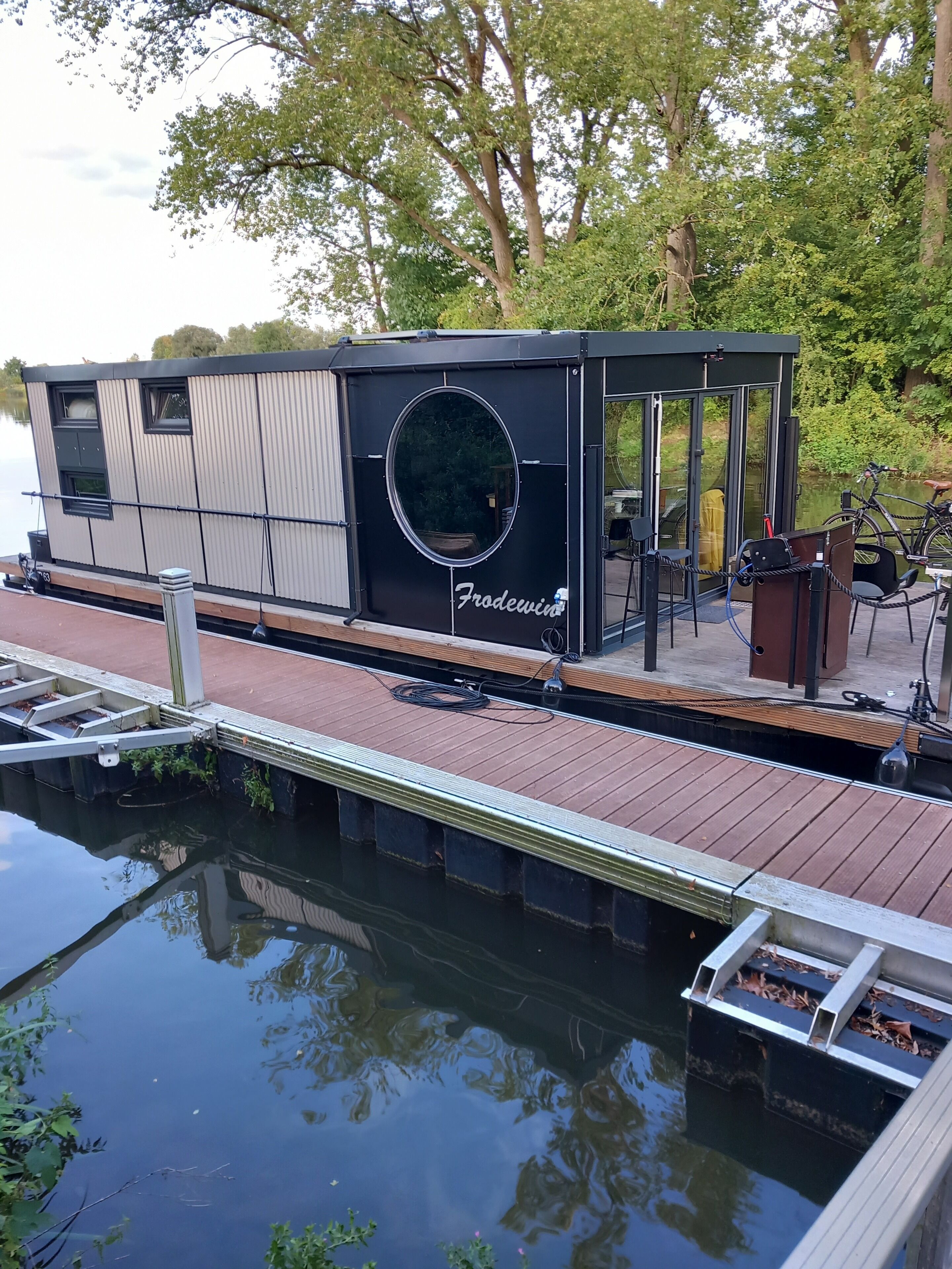 A stationary boat with a covered seating area, a circular window, and the name "Frodewind" visible.