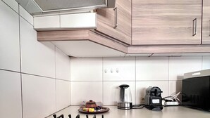 Une cuisine moderne dotée d’une cuisinière à gaz, de meubles blancs et d’une hotte en acier inoxydable.