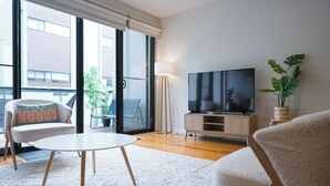 Un salon moderne doté d’un téléviseur à écran plat, d’une table ronde blanche et de deux canapés agrémentés de coussins à motifs.