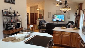 A modern kitchen with a central island, wooden cabinets, and a coffee bar area.