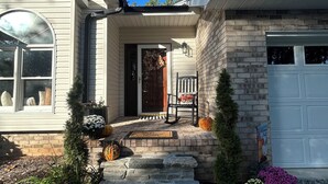 A house with a front porch, a brick garage, and a welcome mat.