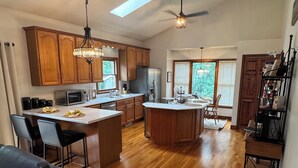 A spacious kitchen with wooden cabinets, a central island, and a dining area with chairs.