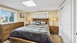 Un dormitorio con cama, cómoda de madera, mesitas de noche y armario.